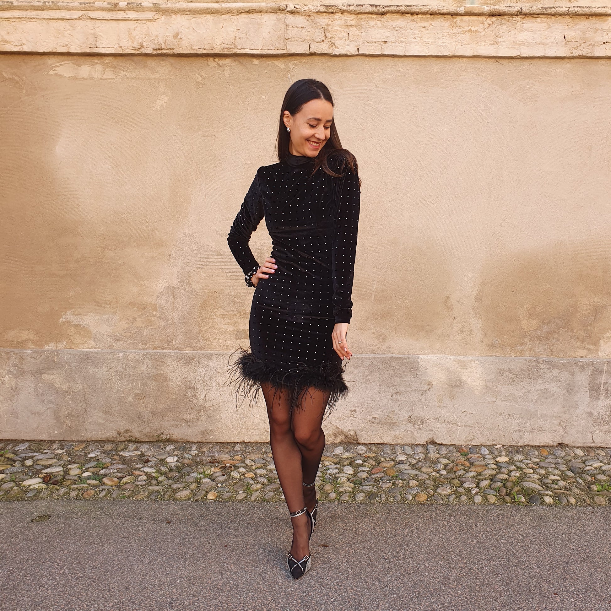 Abito da donna in velluto nero con dettagli in strass e piume, manica lunga e lupetto, ideale per un evento elegante a Fossano
